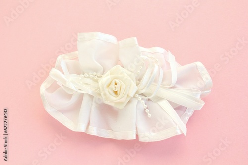 Handmade white wedding hair bow barrette on pink background. Elegant fashion design accessory for woman. Evening hairstyle silk ribbon. Hairpin for girl. Bridal clasp clips with jewellery details © Lidia