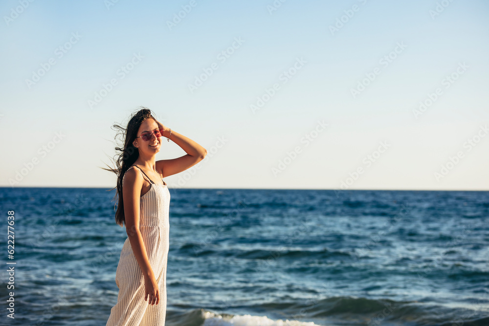 Teenage girl enjoys a beautiful view of the sea and the sunset. Concept of travel, vacation.