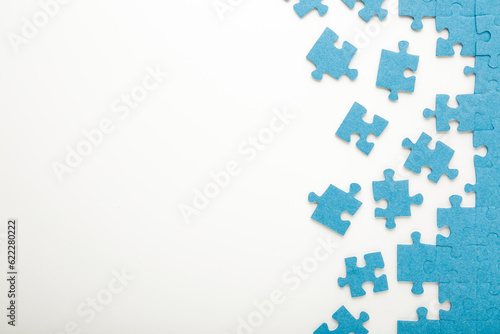 Foto Unfinished blue puzzle pieces on white table background