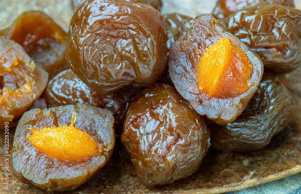 Close-up of Flavored preserved chinese plums (Preserved fruits) on wooden background. Its flavour has sour, salty and sweet taste. Space for text, Selective Focus. Close-up of Flavored preserved chinese plums (Preserved fruits) on wooden background. Its flavour has sour, salty and sweet taste. Space for text, Selective Focus.