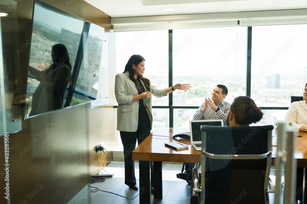 Businesswoman giving presentation to coworkers in office boardroom