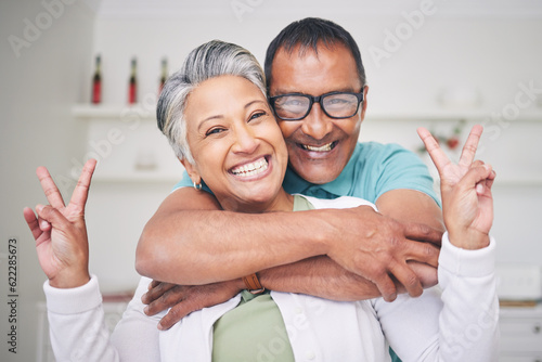 Peace sign  love and smile with portrait of old couple for support  happy and relax. Happiness  kindness and peace with senior man and woman hugging at home for embrace  trust and retirement
