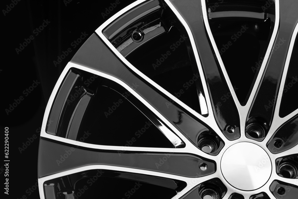 Fototapeta premium Close-up of an aluminum cast wheel from a car with black spokes on a black background