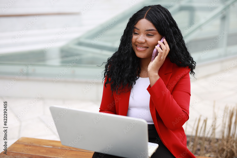 Fototapeta premium beautiful african female with laptop is calling by phone
