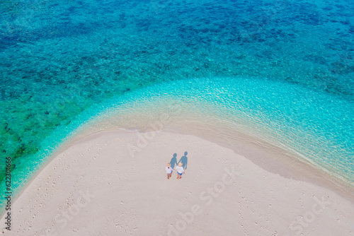 a couple of men and women at a white sandbank in the ocean of Koh Lipe Island Southern Thailand, with turqouse colored ocean and white sandy beach sandbar at Ko Lipe on a sunny day