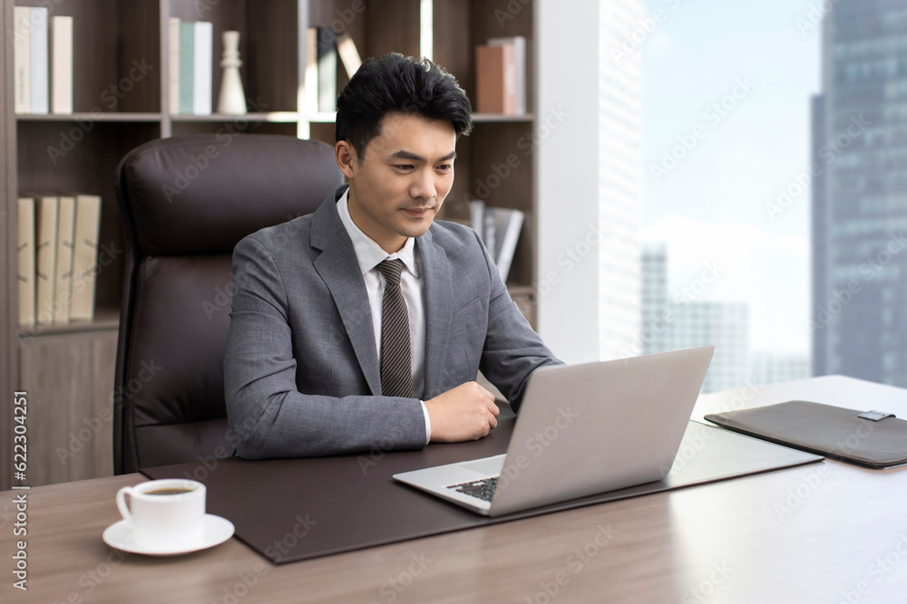Successful Chinese businessman using laptop in office Successful Chinese businessman using laptop in office