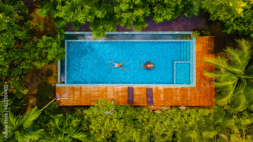 couple of men and women in a swimming pool in the jungle of Krabi Thailand, aerial view with a drone above swimming pool in the jungle of Thailand.
