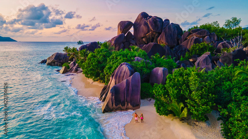 Anse Source d'Argent beach, La Digue Island, Seyshelles, Drone aerial view of La Digue Seychelles bird eye view.of tropical Island, couple men and woman walking at the beach during sunset at a luxury