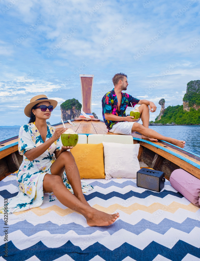 Luxury Longtail boat in Krabi Thailand, couple man, and woman on a trip to the tropical island 4 Island trip in Krabi Thailand with Chicken Island in the background.