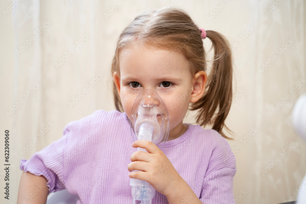 Cute little girl inhaling mist form nebulizer at home. Holding mask over her nose and mouth Cute little girl inhaling mist form nebulizer at home. Holding mask over her nose and mouth
