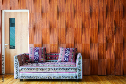 Comfortable batik-patterned sofa near the door with a backdrop of raised wooden wall ornaments