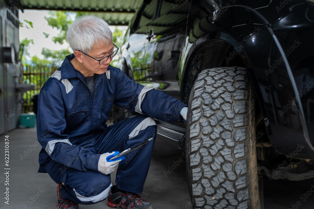 An elderly man in uniform is checking tires. concept of auto repair service