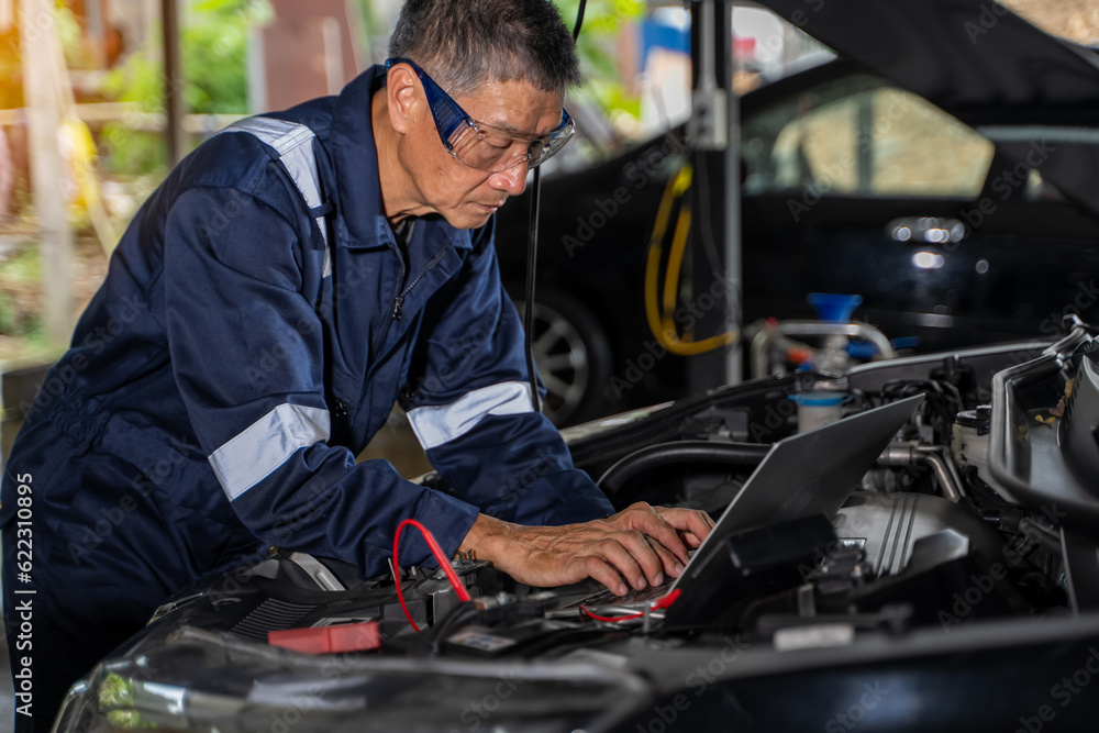 Close-up view of auto mechanic using technology working on car engine in garage. Repair service.