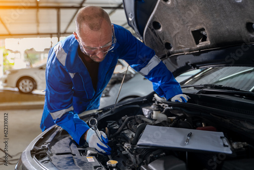 Close-up view of auto mechanic working on car engine in garage. Repair service