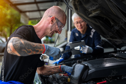 Close-up view of auto mechanic working on car engine in garage. Repair service © Surachai