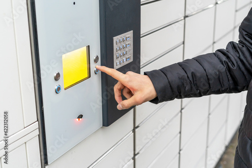 A man near the self-service mail terminal. Parcel delivery machine. Person holding a cardboard box. Mail delivery and post service, online shopping, e commerce concept photo