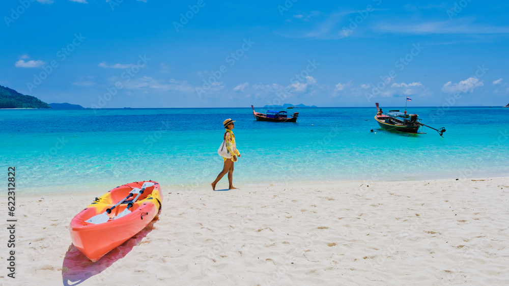 Koh Lipe Island Southern Thailand with turqouse colored ocean and white sandy beach at Ko Lipe. a Asian Thai woman on vacation in Thailand relaxing at the beach looking at the ocean