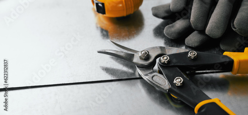 tinsmith and metal works. tin snips, gloves and ruler on metal sheets. banner with copy space