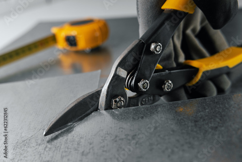 tinsmith cutting metal sheet with tin snips