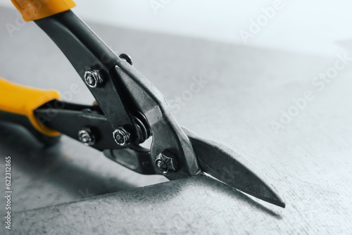 closeup of metal scissors cutting a tin sheet photo