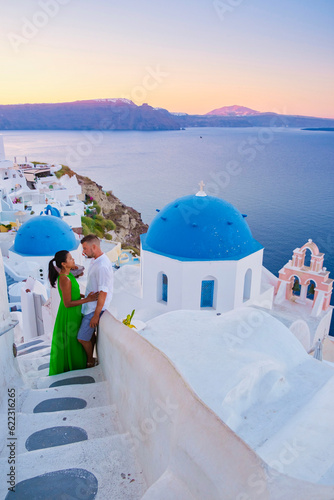 Couple hugging and kissing on a romantic vacation in Santorini Greece  men and women visit the whitewashed Greek village of Oia .