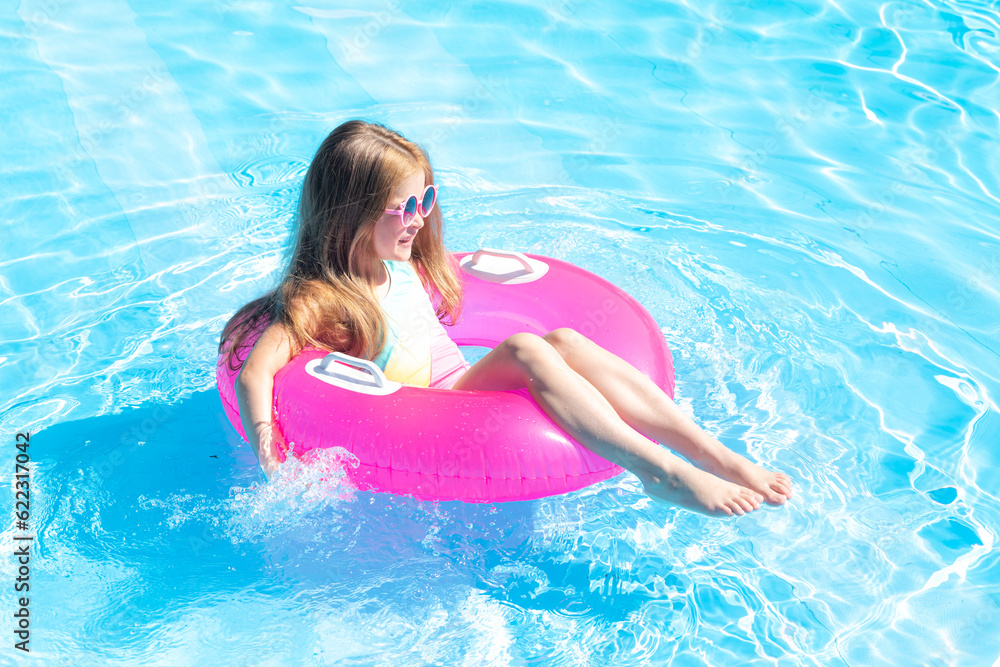 happy little girl swims in the pool in summer in sunglasses, space for text