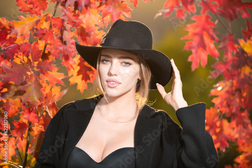 Autumn woman with fall yellow maple leaf, outdoor portrait. Beautiful model with autumn leaves, fall yellow maple in autumnal park. Autumn girl enjoying warm sunny weather in autumn fall season. © Volodymyr