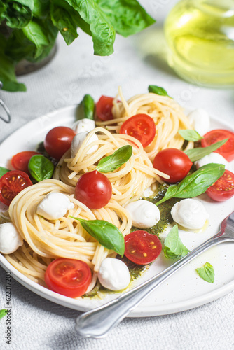 Spaghetti with mozzarella, tomatoes, basil and pesto sauce. Pasta Caprese