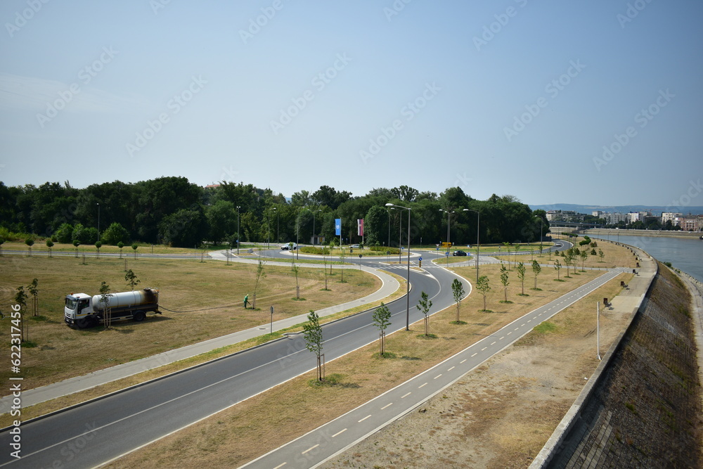 Fototapeta premium ˝Novi Sad, Serbia - 07 11 2023: Public workers watering trees near Danube River˝