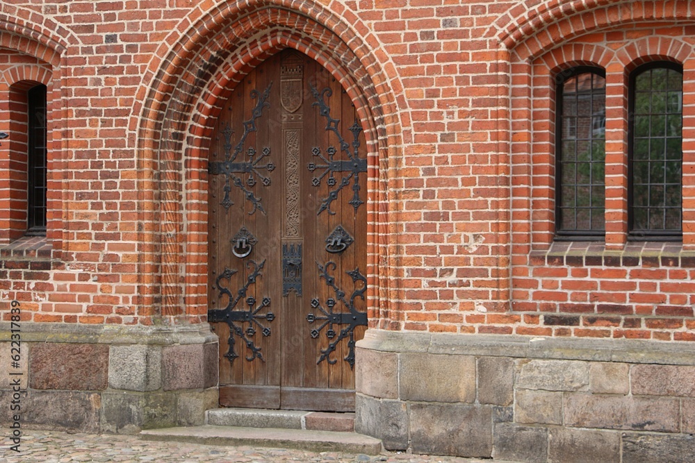 closeup of a very old large wooden door of a church with metallic decorations on the wood
