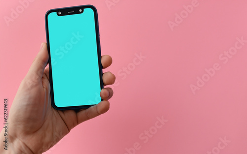 A hand holding a mobile phone. Pink background, pastel colors. Technology, keep in touch. AI generative