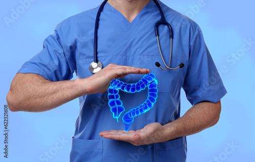 Fototapeta Gastroenterologist holding illustration of large intestine on light blue backgro