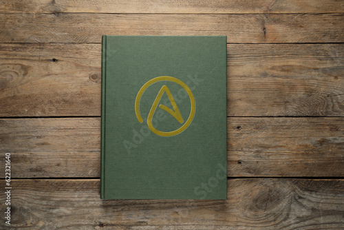 Photos Book with atheism symbol on wooden background, top view