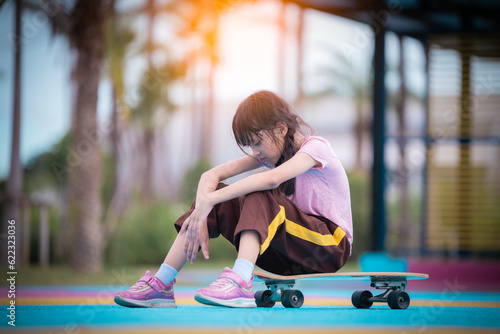 Fototapeta Naklejka Na Ścianę i Meble -  Portrait of happy asia girl pose tried sitting on board while riding on skateboard in public childrean park is extheam sport relaxing on holiday .