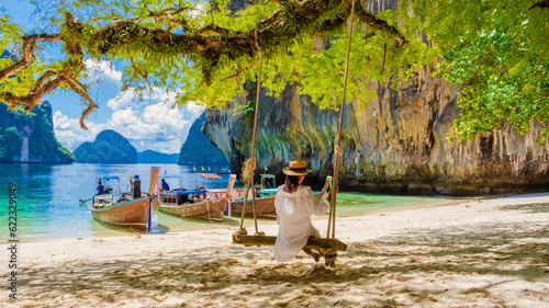 women on a swing at the Tropical lagoon of Koh Loa Lading Krabi Thailand part of the Koh Hong Islands in Thailand. beautiful beach with limestone cliffs and longtail boats photo