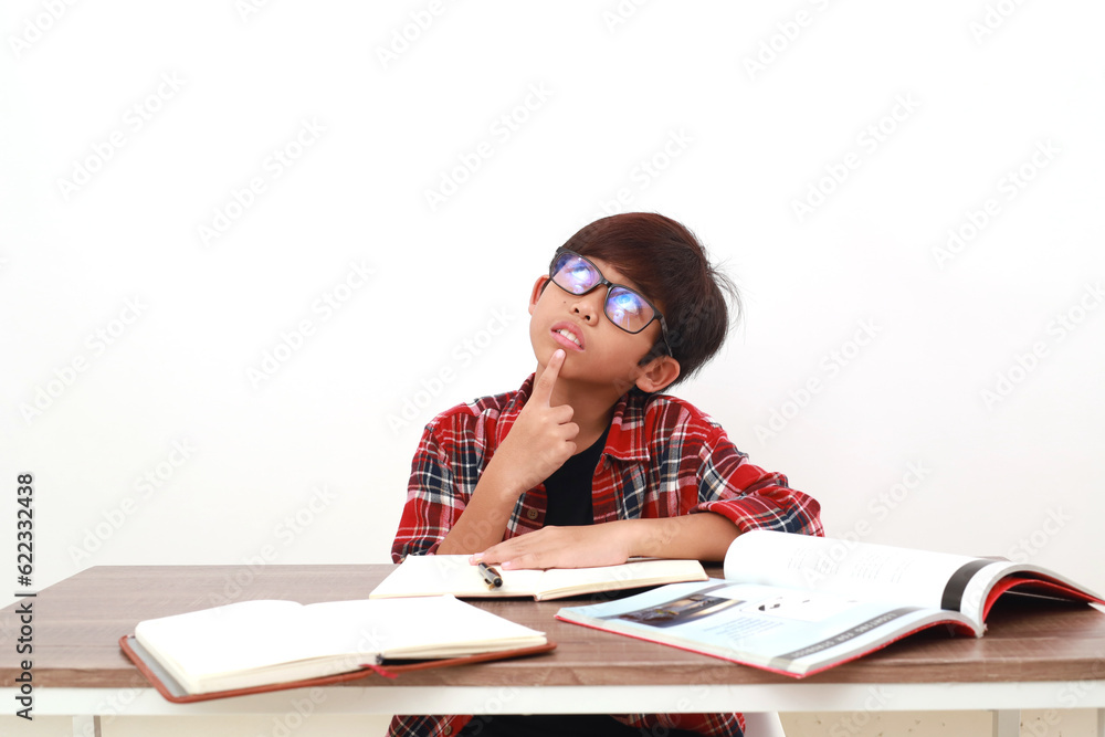 Thoughtful asian student dreaming something while studying on the desk Thoughtful asian student dreaming something while studying on the desk