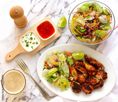 Roasted chicken wings with salad, top view
