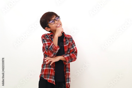 Handsome asian boy standing while thinking something and looking sideways