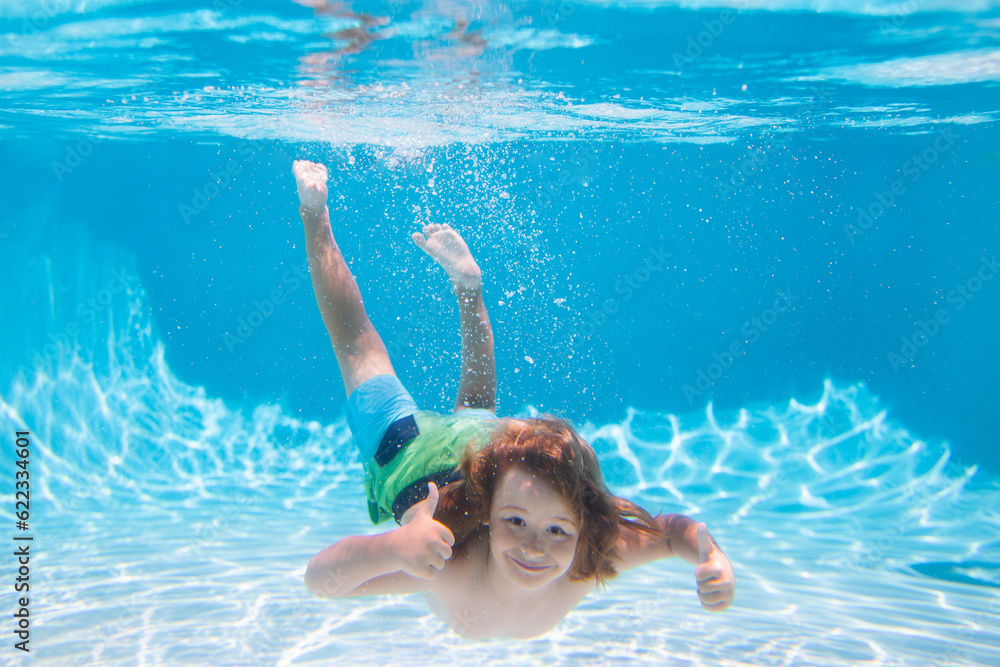 Underwater boy in the swimming pool. Cute kid boy swimming in pool under water. Summer kids activity, watersports.