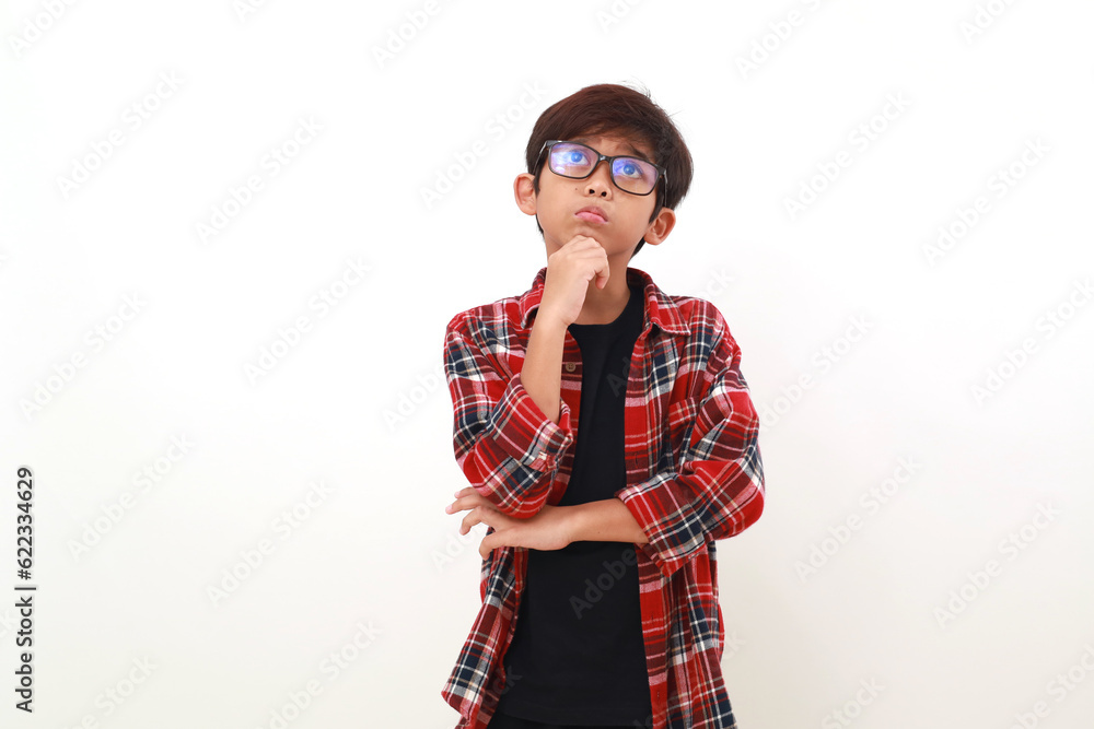 Fototapeta premium Thoughtful asian boy standing while looking above. Isolated on white
