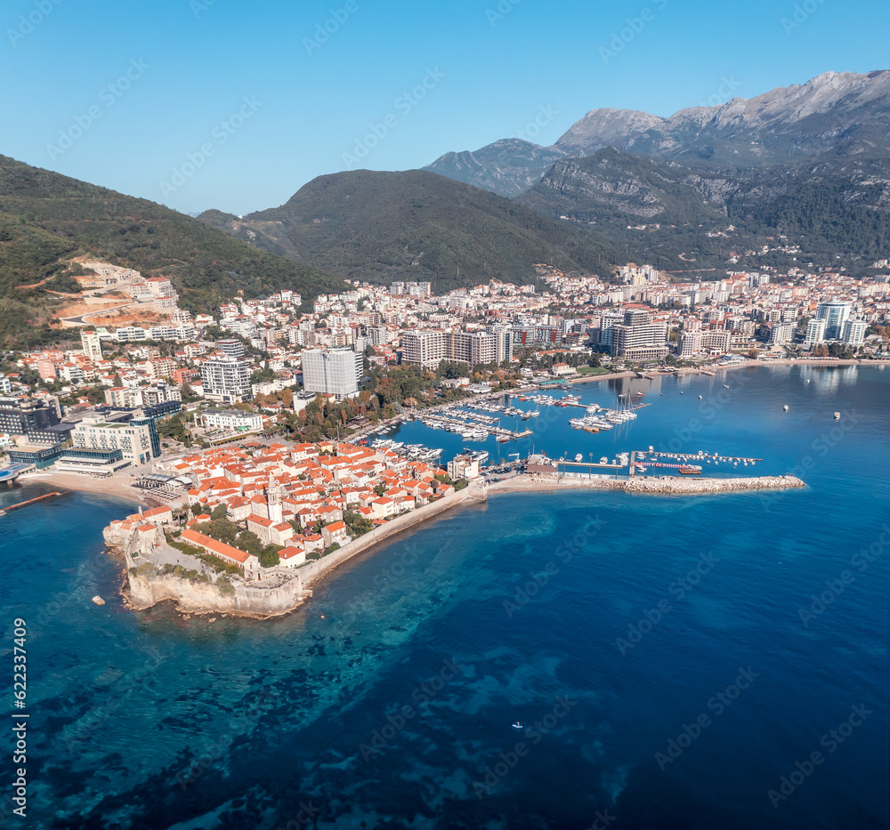 Amazing panoramic view with the city of Budva in Montenegro, old town, houses with red roofs and marina with boats