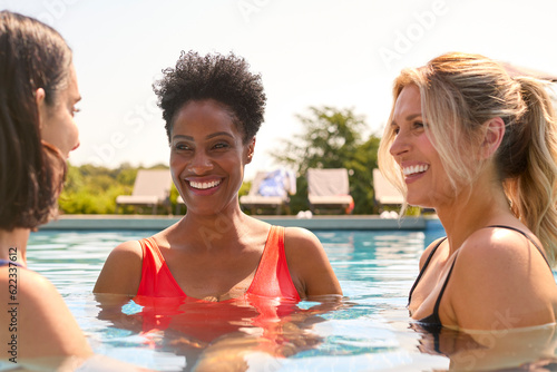 Three Mature Female Friends Wearing Swimsuits In Outdoor Pool On Spa Day