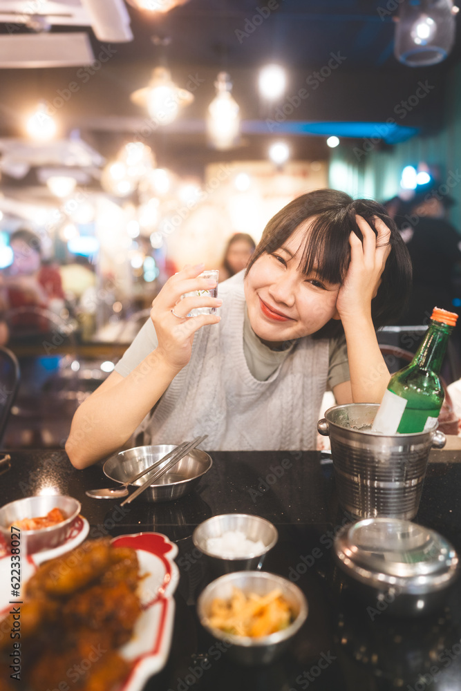 Portrait of drunk asian woman drinking soju or sake at alcohol korean bar restauran