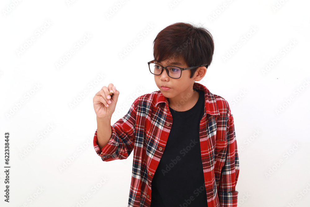 Adorable asian boy holding a pen while writing something. Isolated on white