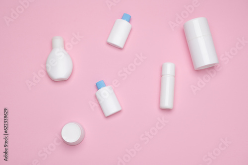 Still life with a set of white small test mockup bottles with cosmetic products for skin and body care, isolated on pink