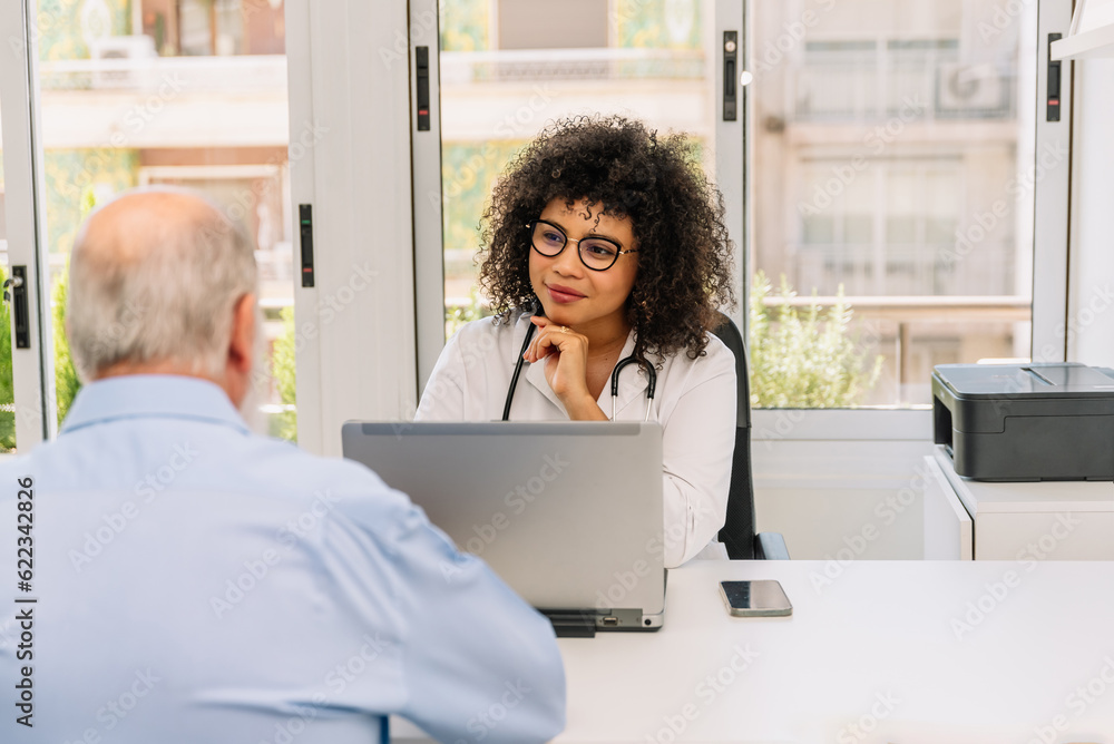hispanic woman doctor sitting at the table with unrecognizable male patient hispanic woman doctor sitting at the table with unrecognizable male patient