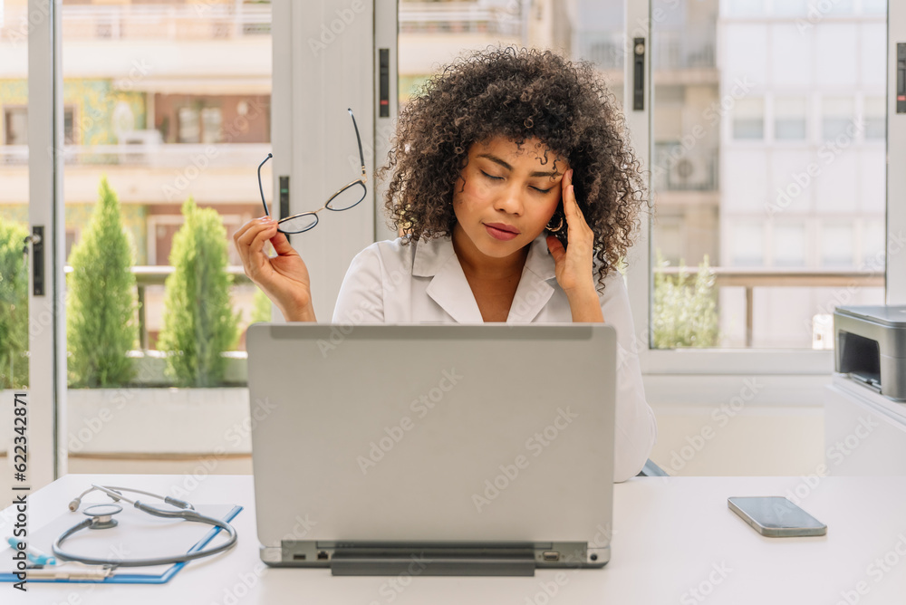 Overworked hispanic female doctor in his office holding her glasses Overworked hispanic female doctor in his office holding her glasses