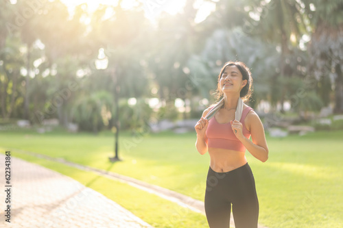 Fit happy smile 30s young Asian woman in sportswear enjoys refreshing sunset run in nature. The silhouette of figure against the setting sun is beautiful sight. Fitness, health, or motivation concept.