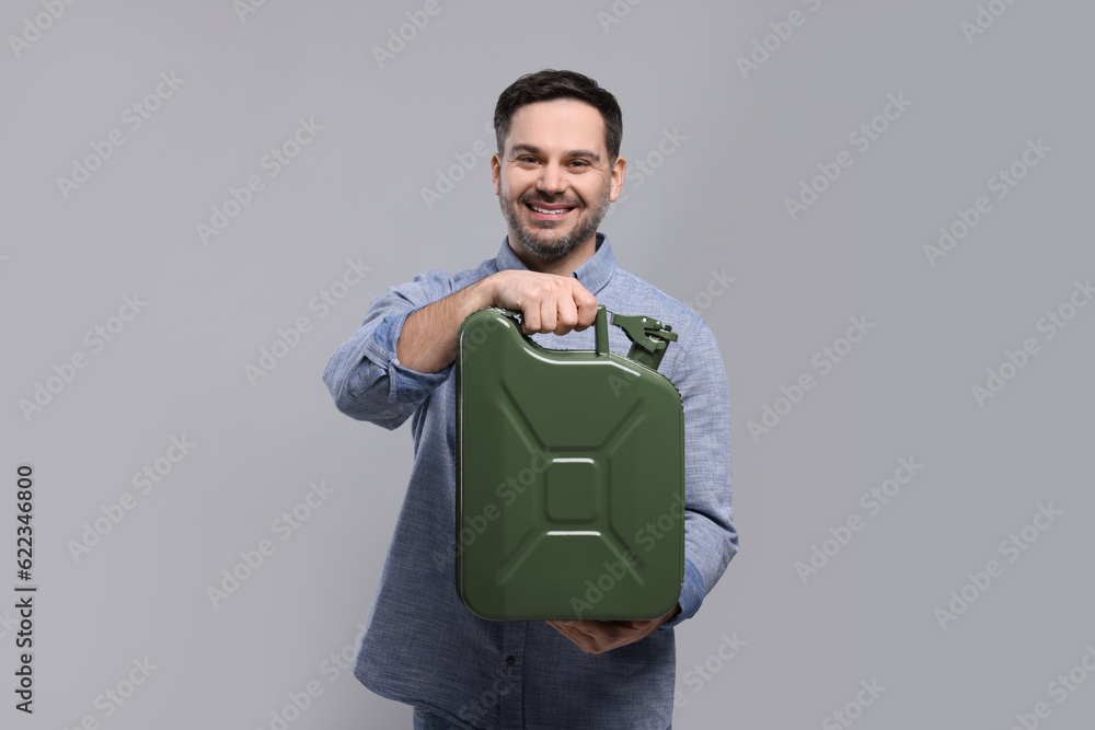 Man holding khaki metal canister on light grey background Man holding khaki metal canister on light grey background