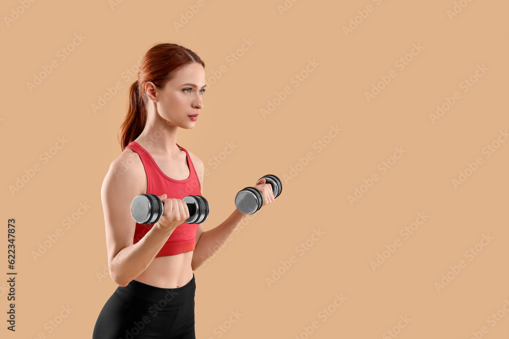 Young woman in sportswear doing exercises with dumbbells on beige background, space for text Young woman in sportswear doing exercises with dumbbells on beige background, space for text